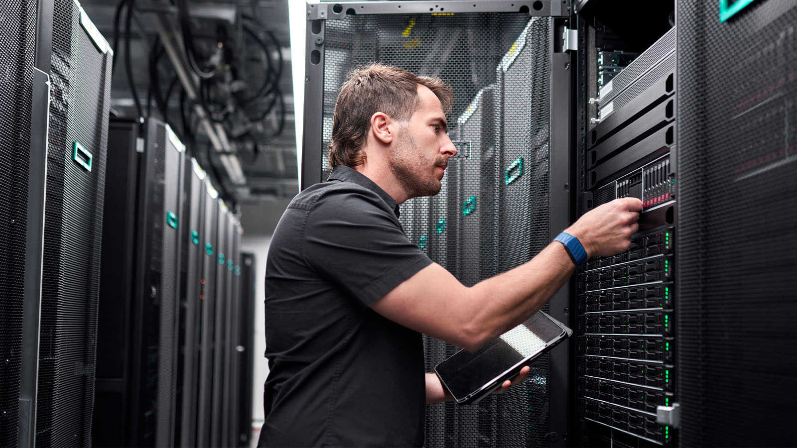 Technician performing hands-on maintenance on rack-mounted server equipment, tools or diagnostic laptop visible.